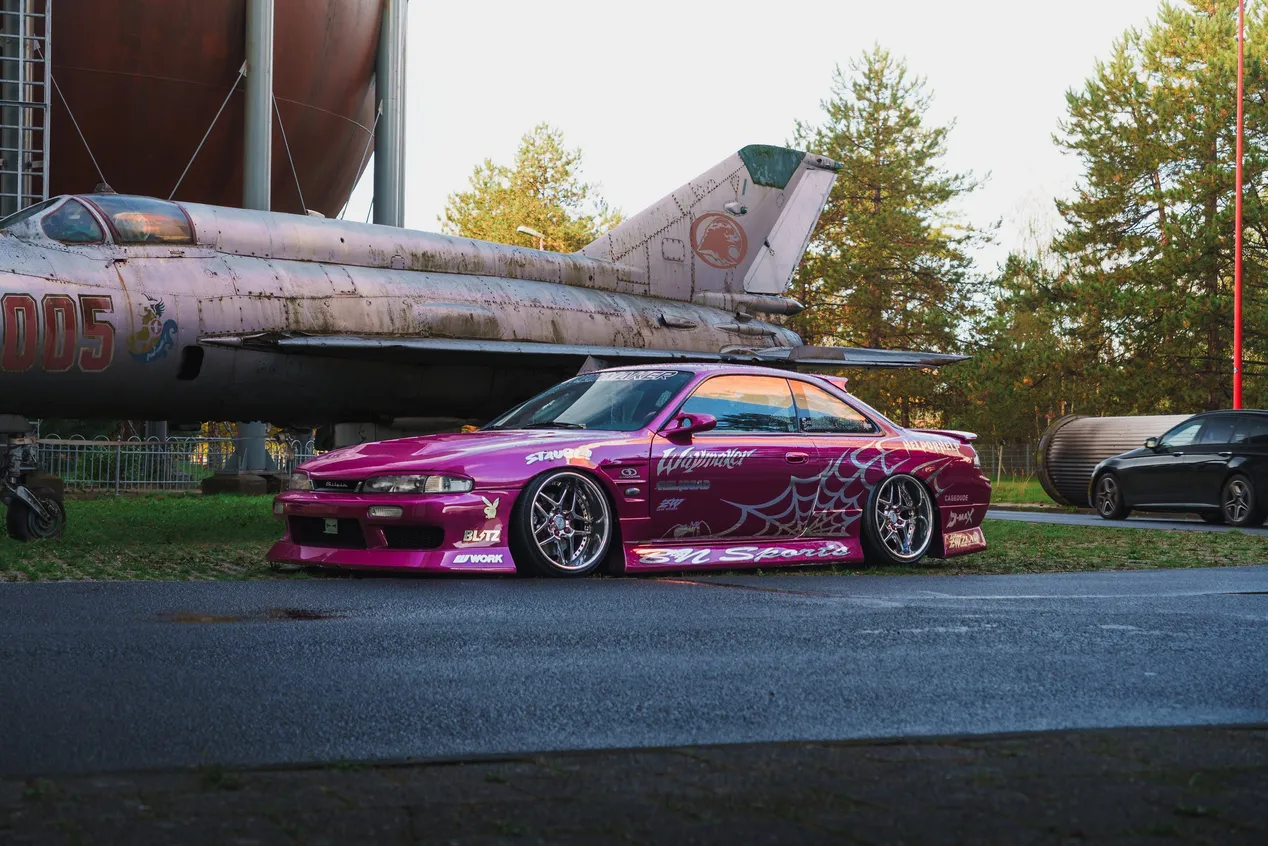 Pinker Nissan Silvia S14 mit Spinnennetz-Design unter einem MiG-Jet