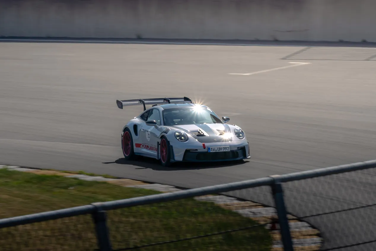 Weißer Porsche 911 GT3 RS mit roten Felgen, Frontdreiviertelansicht in der Kurve