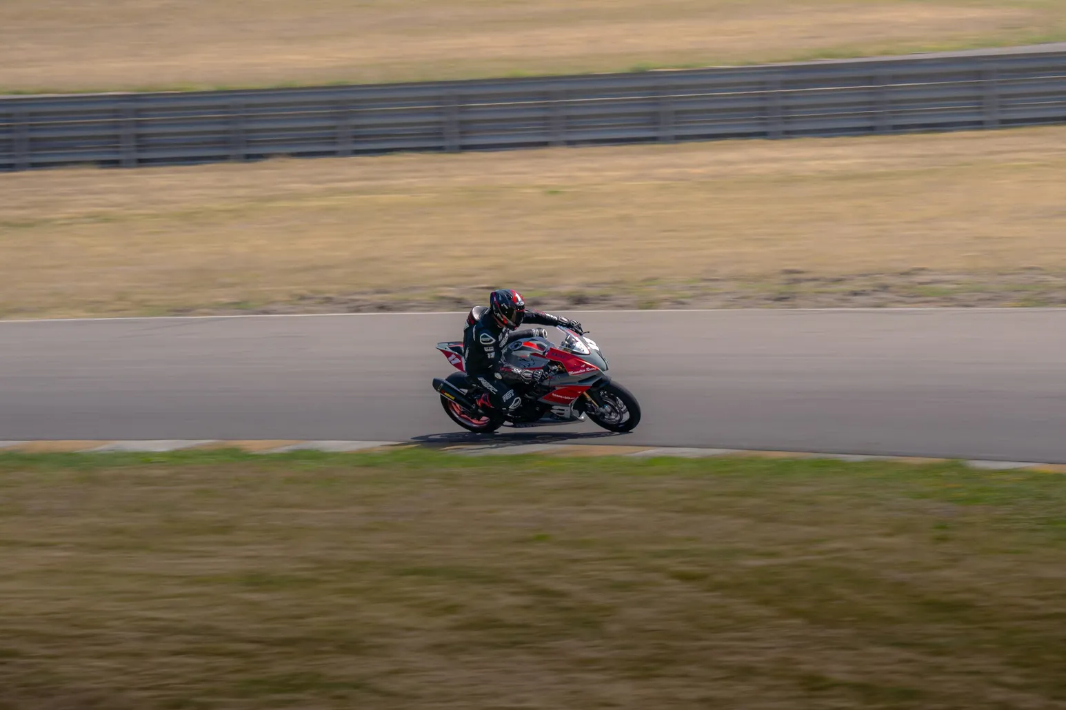 Rider in red leathers leaning a sport bike into the turn