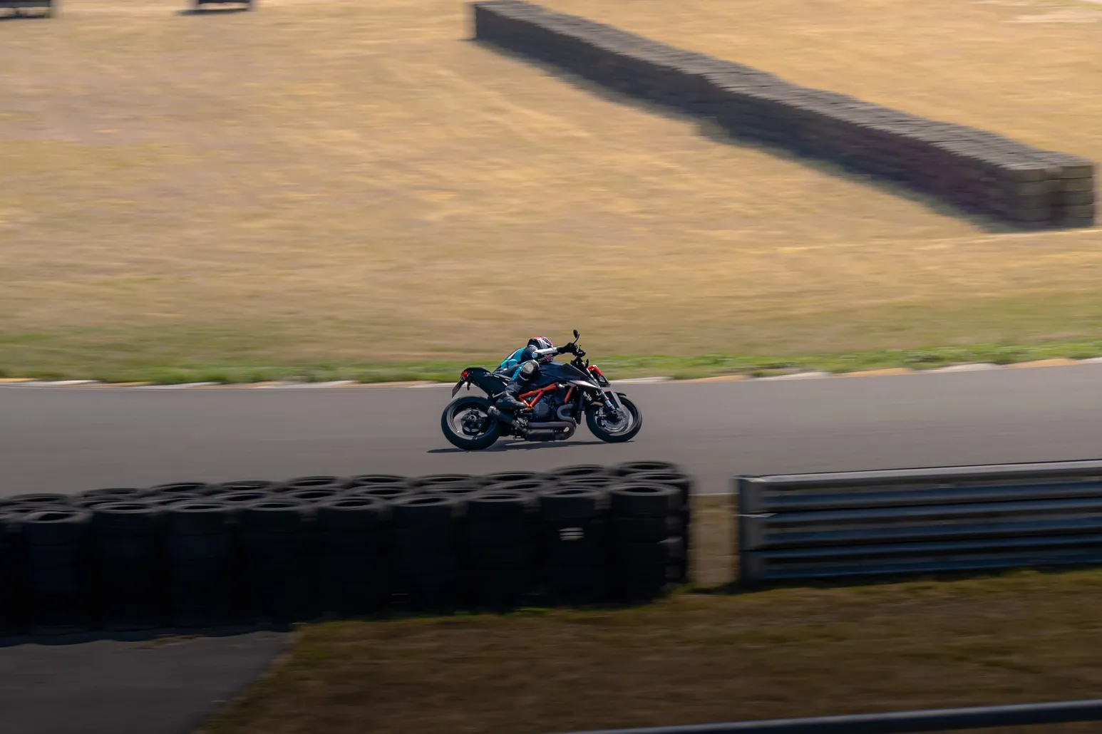 Rider on a dark bike cornering in front of the tyre stack
