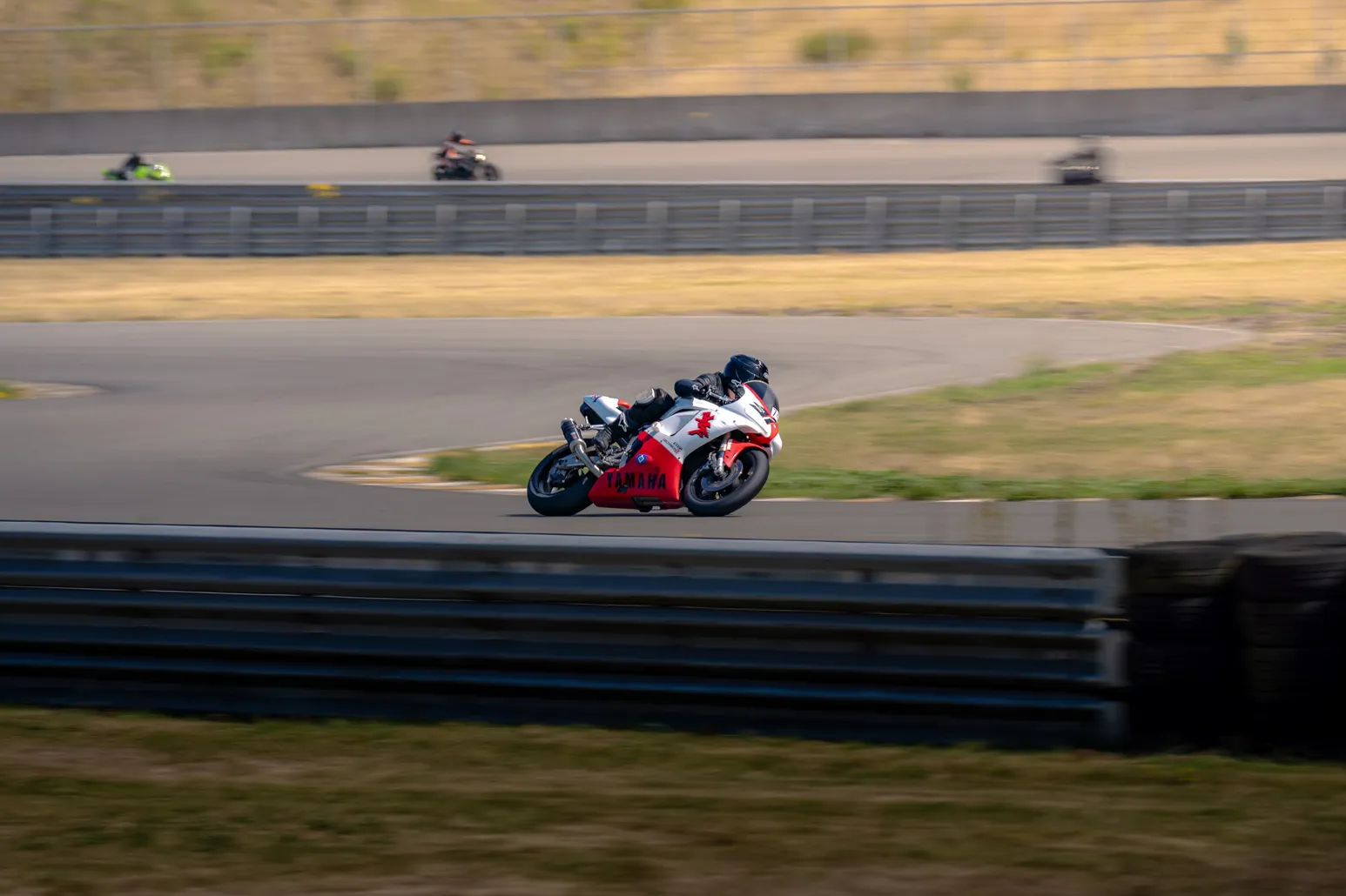 Red and white sport bike cornering with riders behind