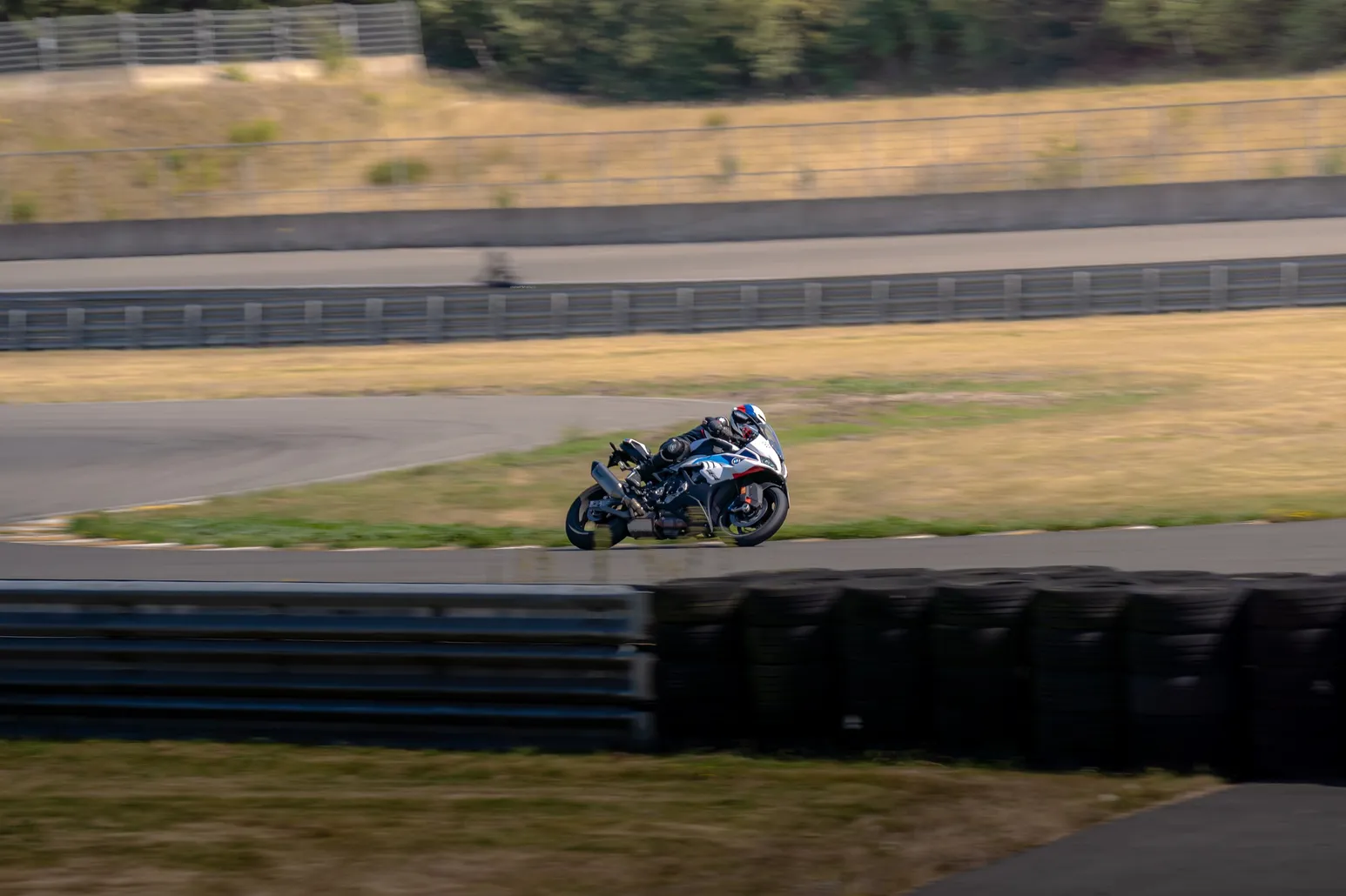 Blue and white sport bike cornering behind the barrier