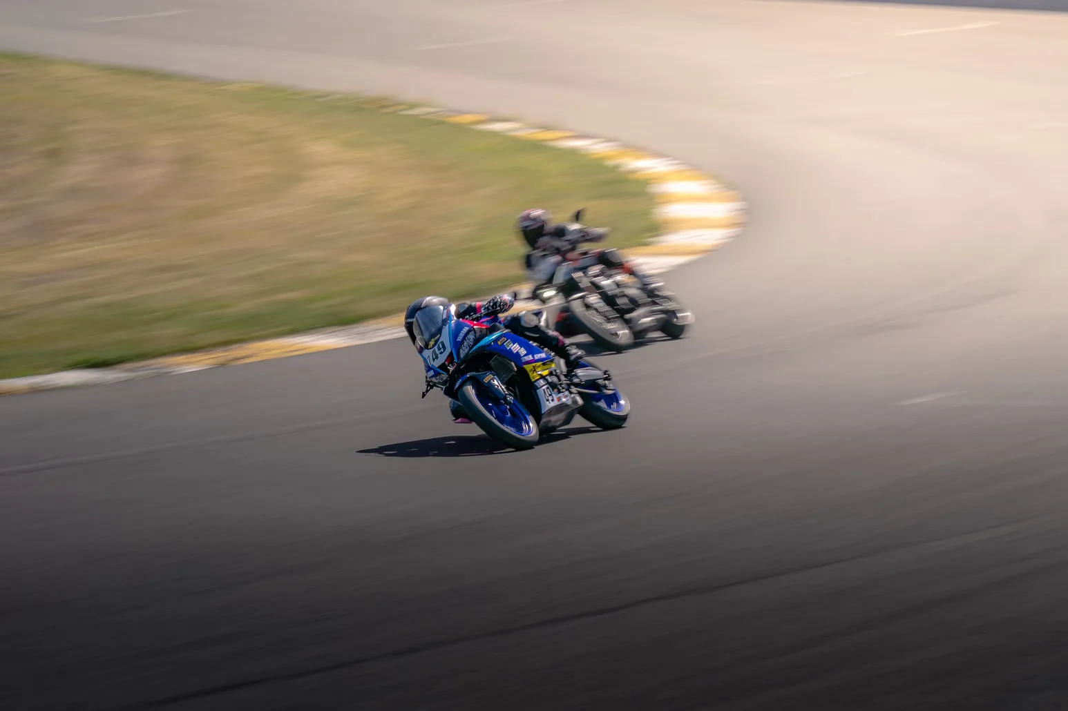 Two riders on blue bikes cornering one behind the other