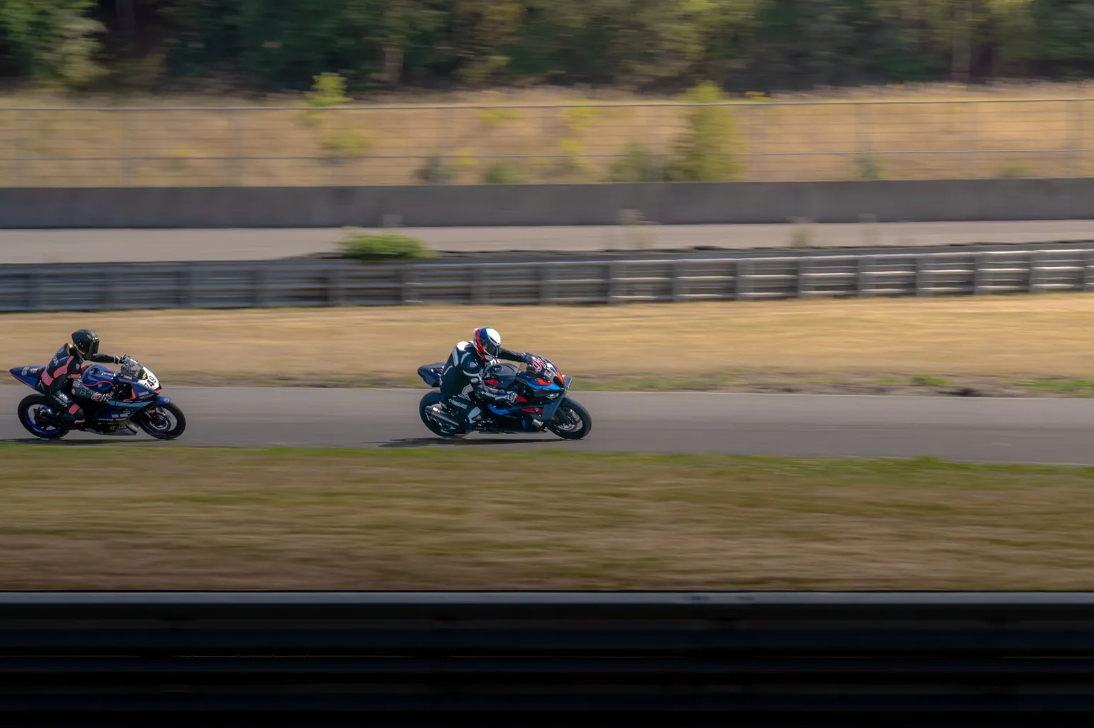 Two riders racing past the barrier