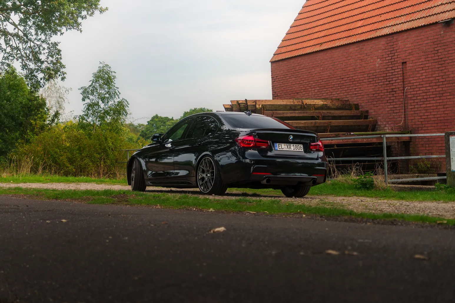 Black BMW F30 rear three-quarter beside a brick building