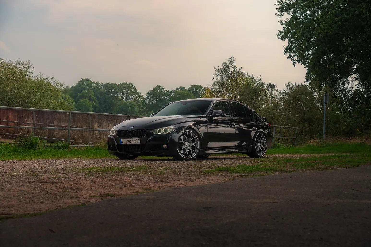 Black BMW F30 three-quarter view with trees