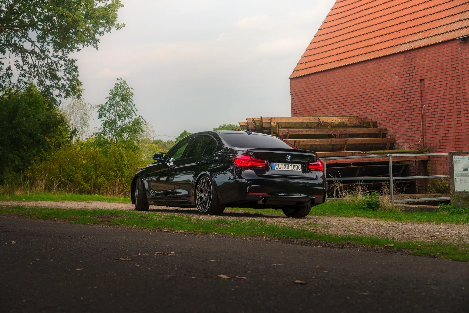 Black BMW F30 rear three-quarter at the brick barn