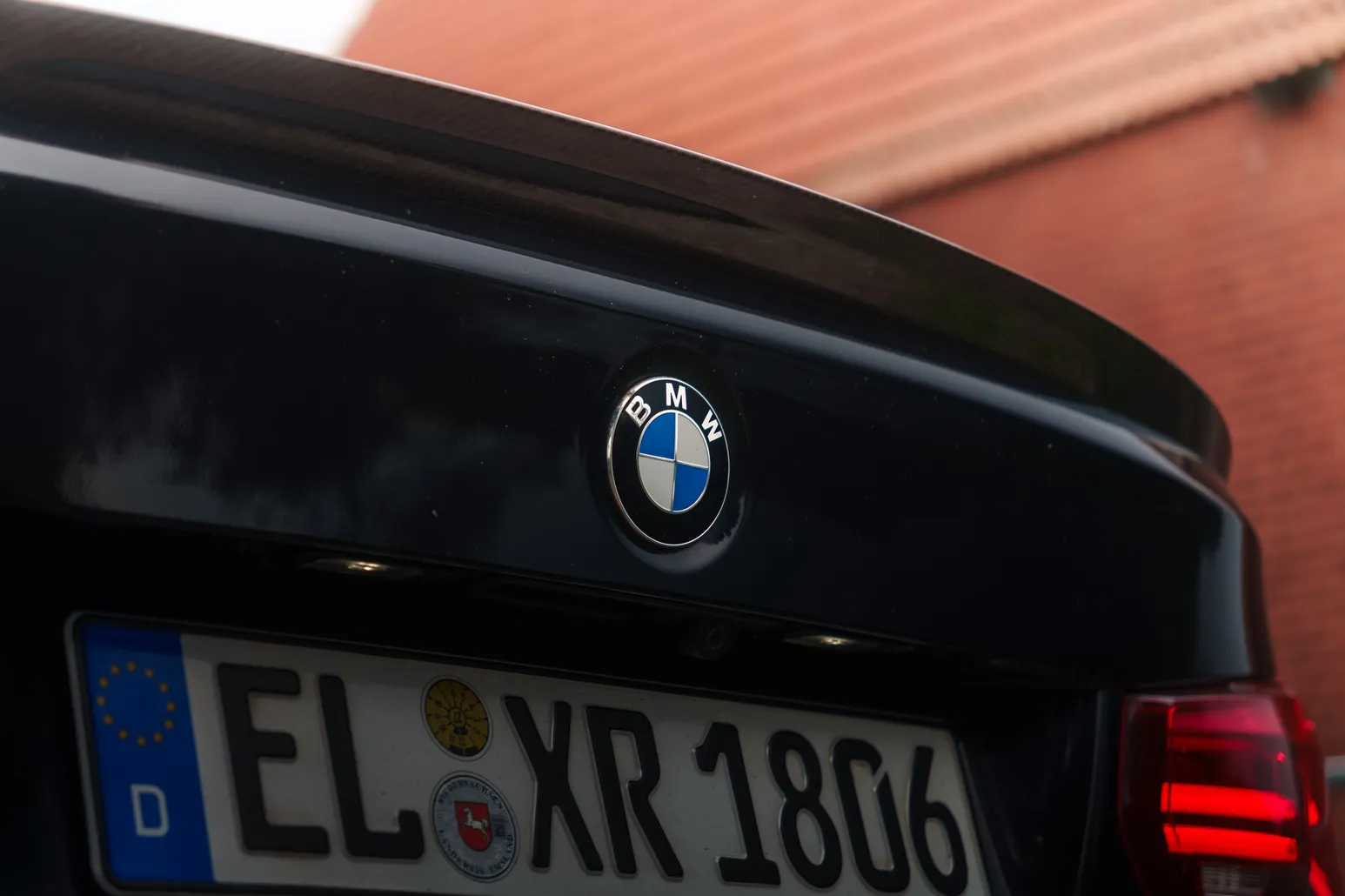 BMW badge on the boot lid with the barn roof reflected