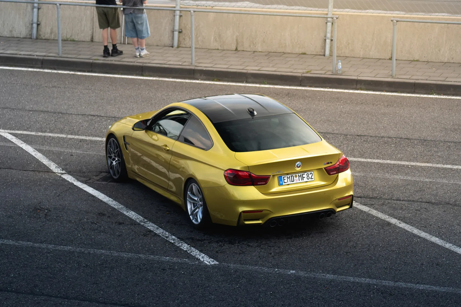 Yellow BMW M4 parked in the paddock, rear view