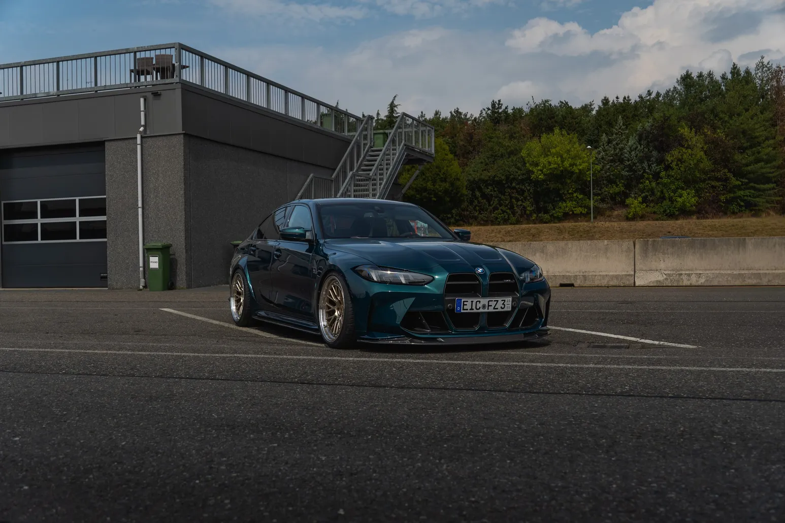 Dark green BMW M3 parked in front of the pit building