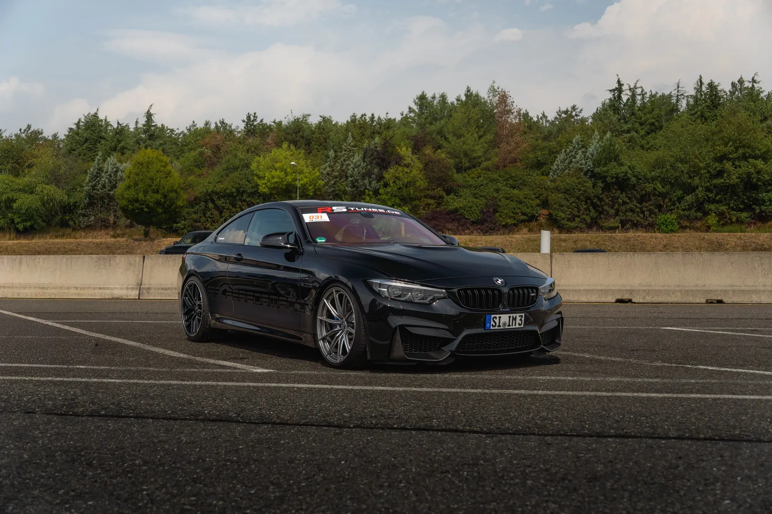 Black BMW M4 front three-quarter in the paddock