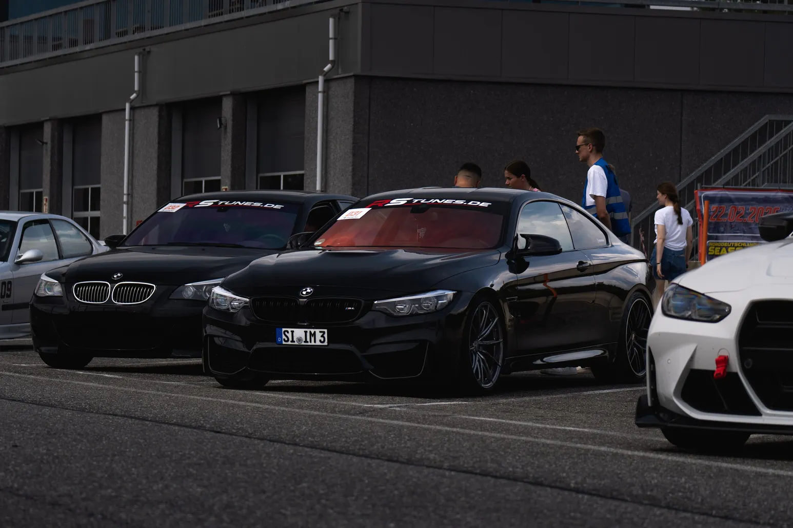 Black BMW M4 among cars by the pit garages