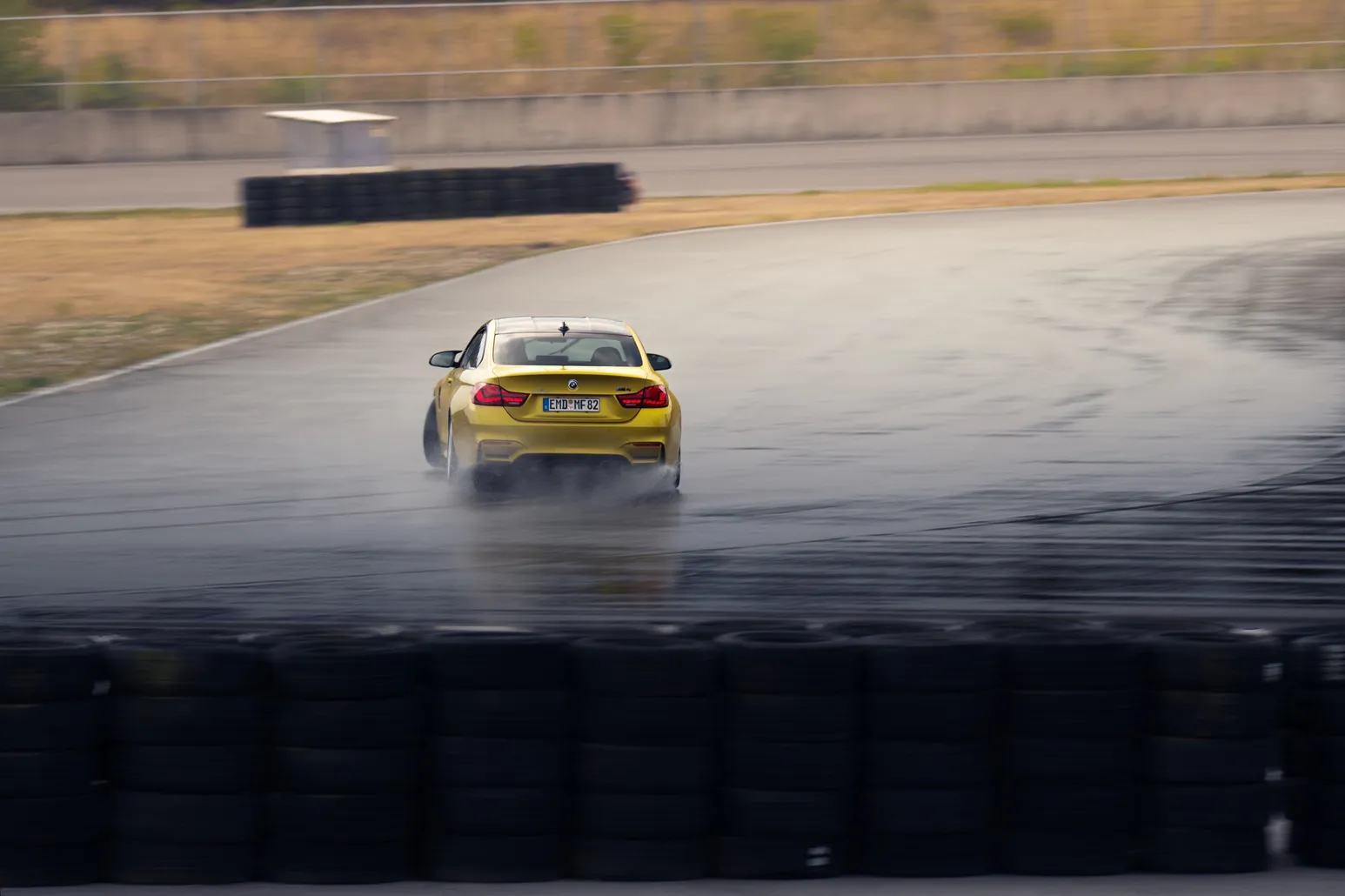 Yellow BMW M4 sliding with spray, front view