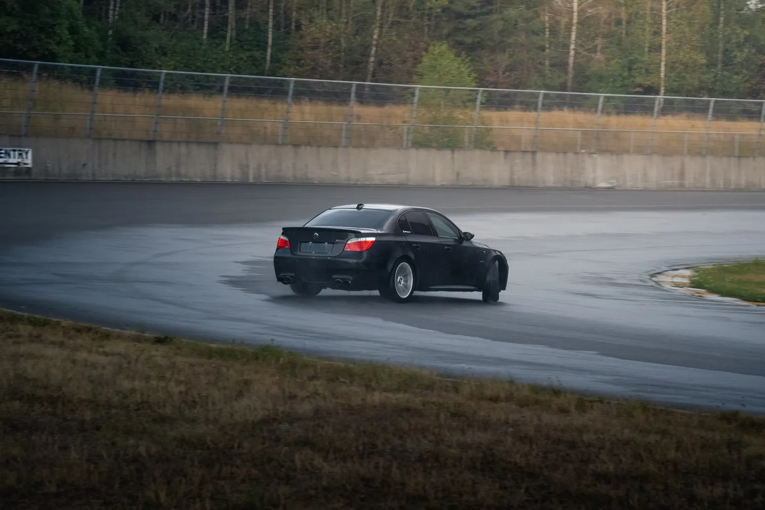 Black BMW M5 drifting on a wet corner