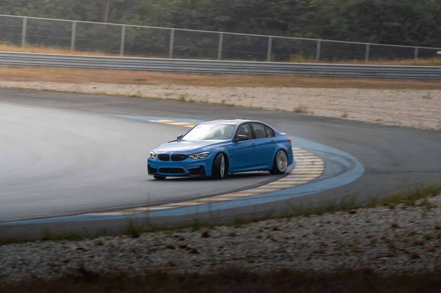 Blue BMW M3 sliding past the kerbs in a panning shot