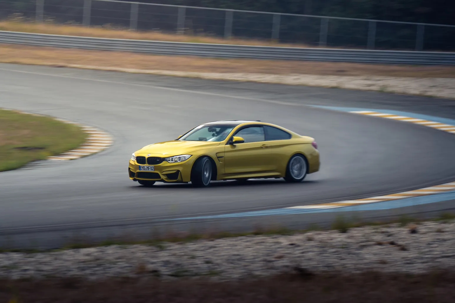 Yellow BMW M4 sliding over the kerb