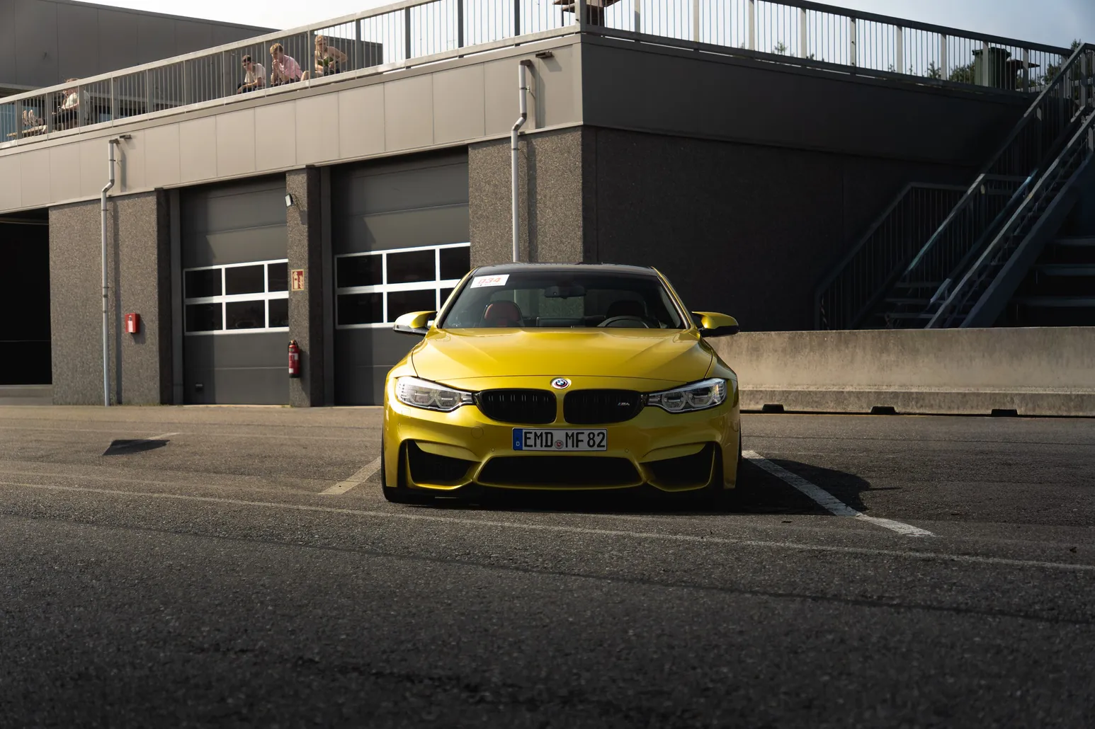 Yellow BMW M4 front view in front of the pit garages