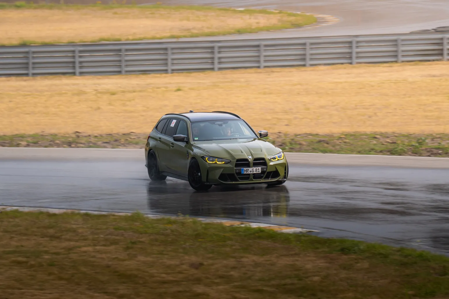Green BMW M3 Touring drifting on a wet corner