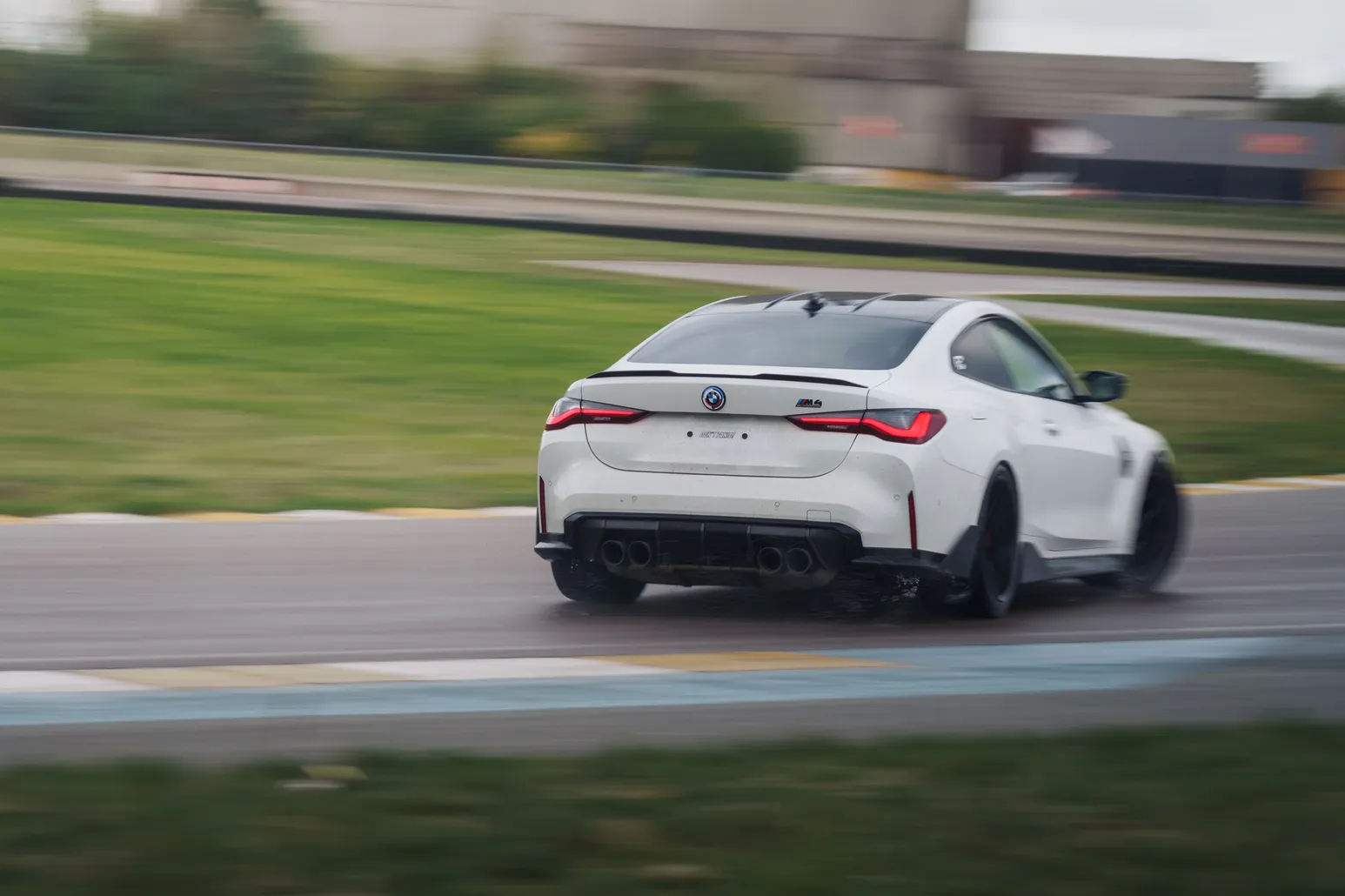White BMW M4 (G82) from behind on corner exit