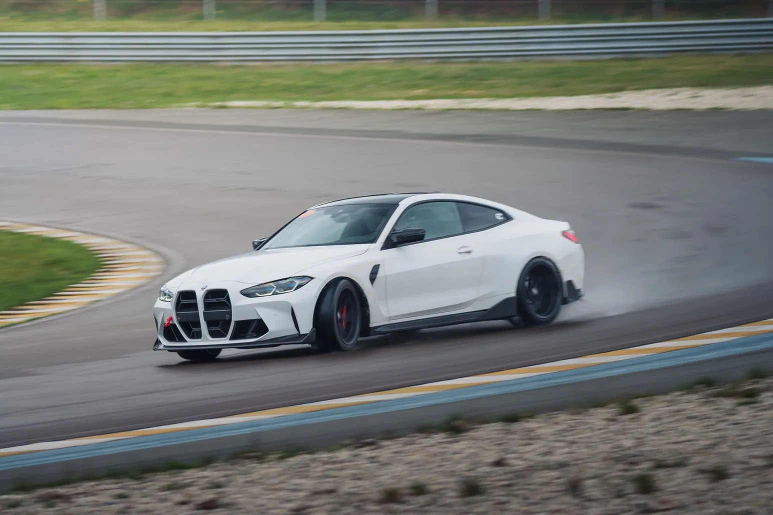 White BMW M4 (G82) sideways across the wet surface