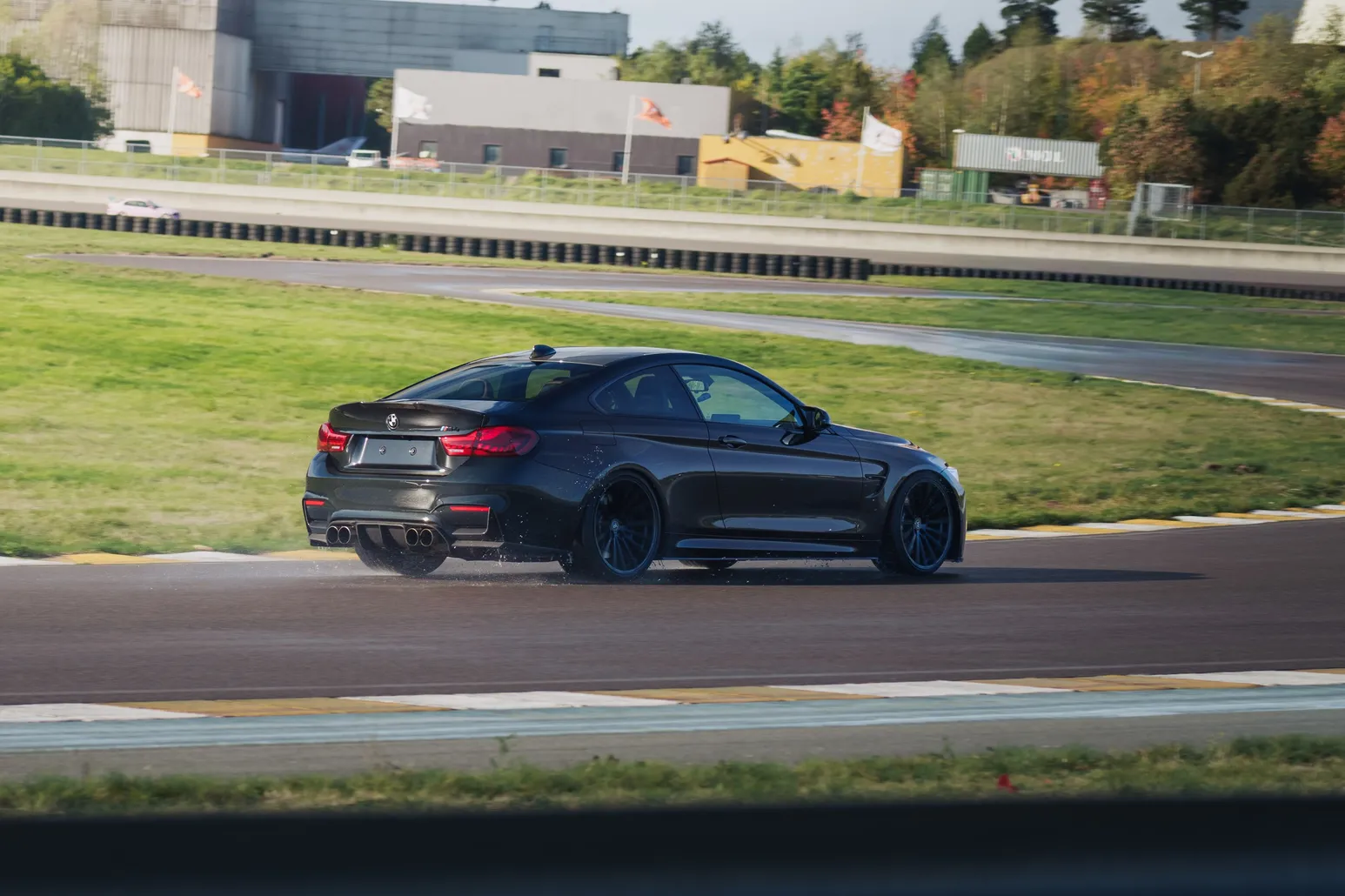 Black BMW M4 (F82) in front of the paddock