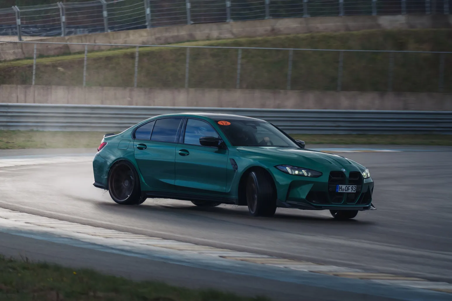 Green BMW M3 (G80) drifting across the wet asphalt