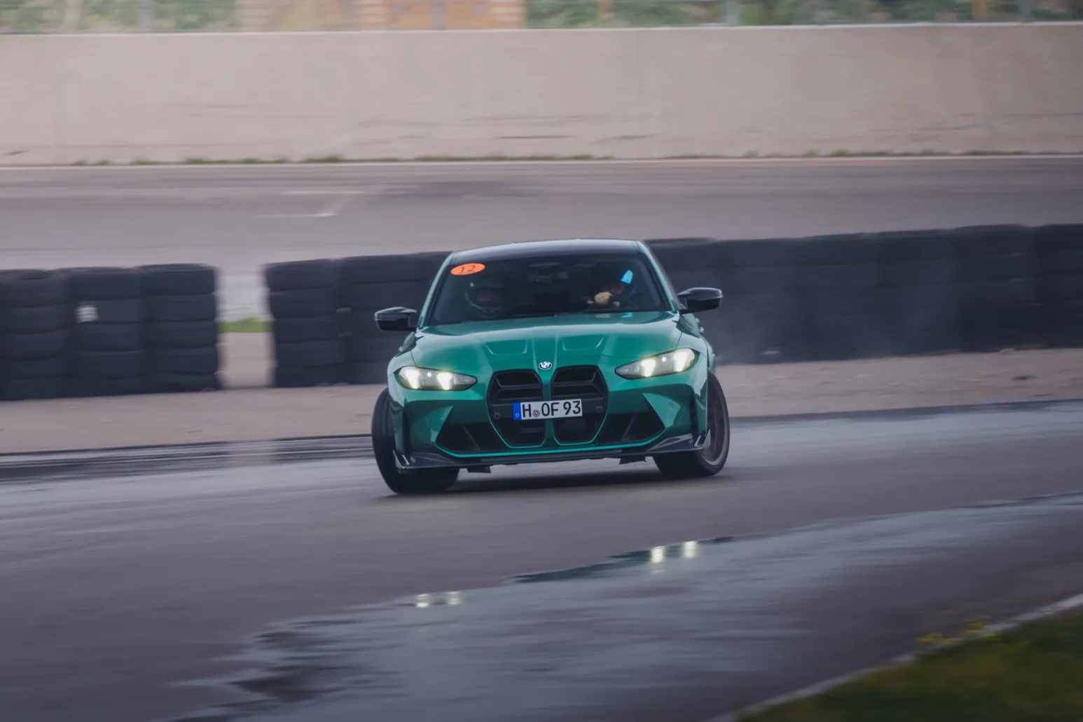 Green BMW M3 (G80) head-on in front of the tyre wall