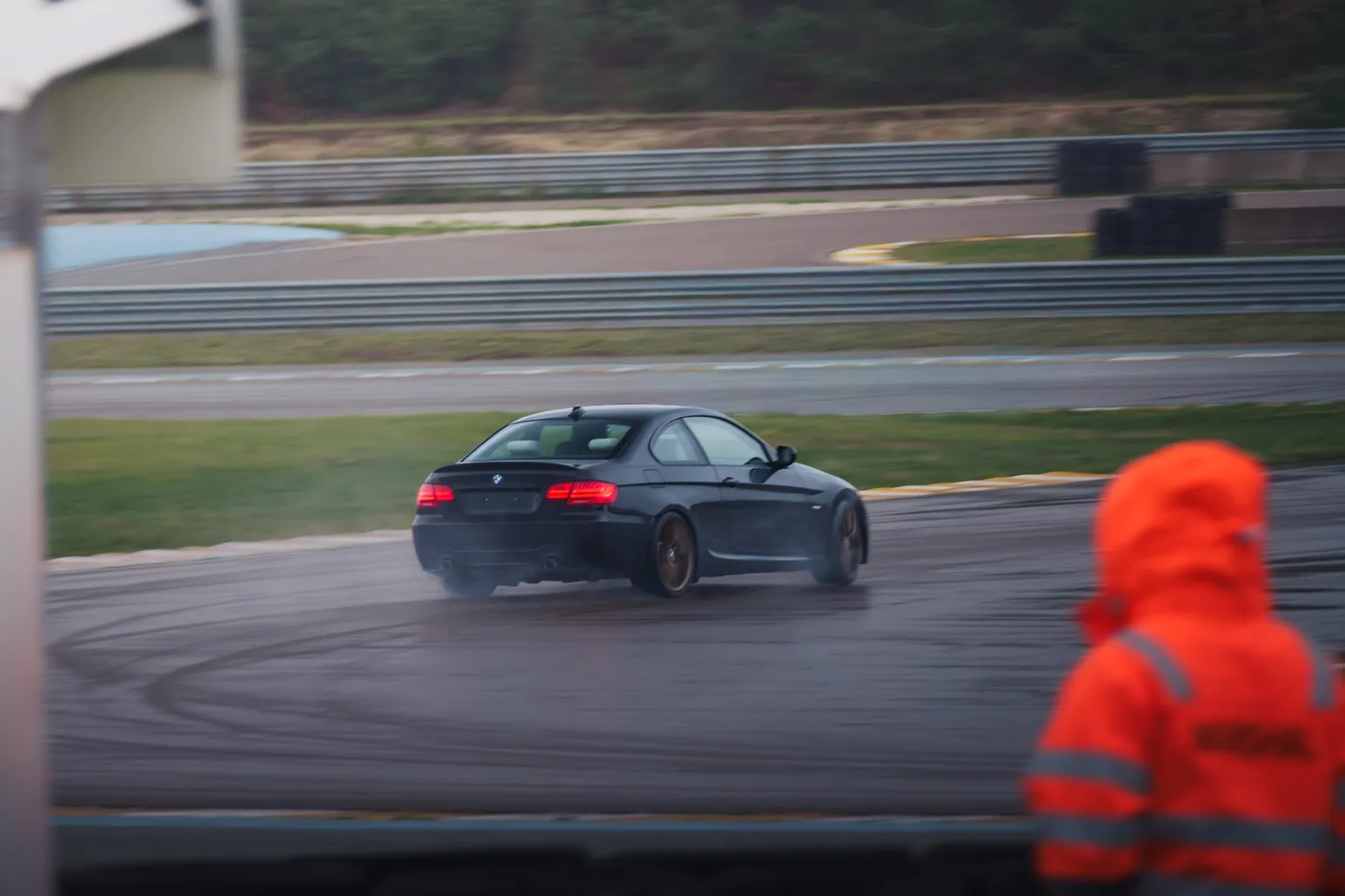BMW E92 drifting with a marshal in orange in the foreground