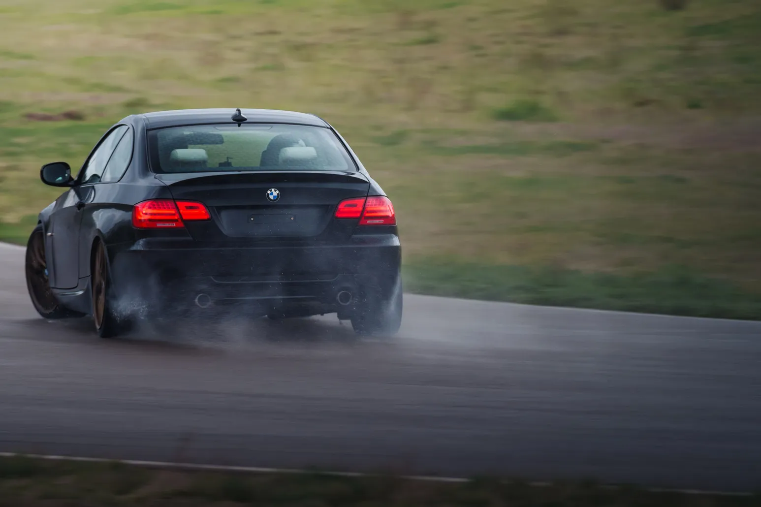 BMW E92 coupé from behind with smoke from the rear tyres