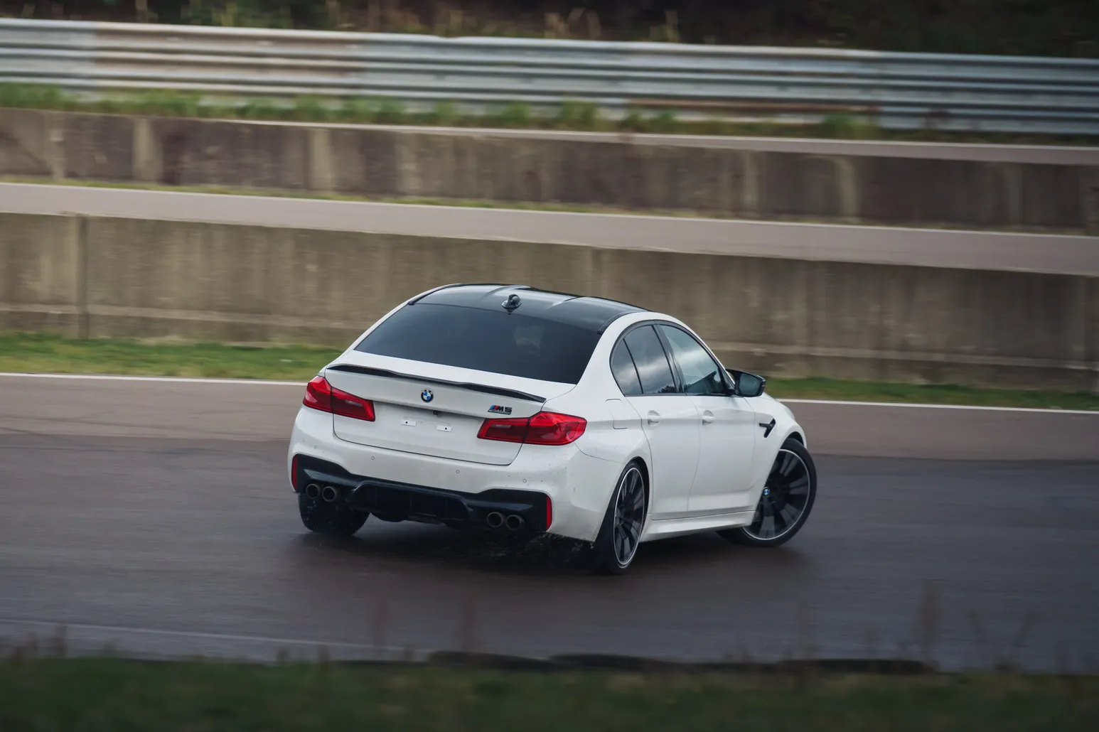 White BMW M5 (F90) from behind in a corner