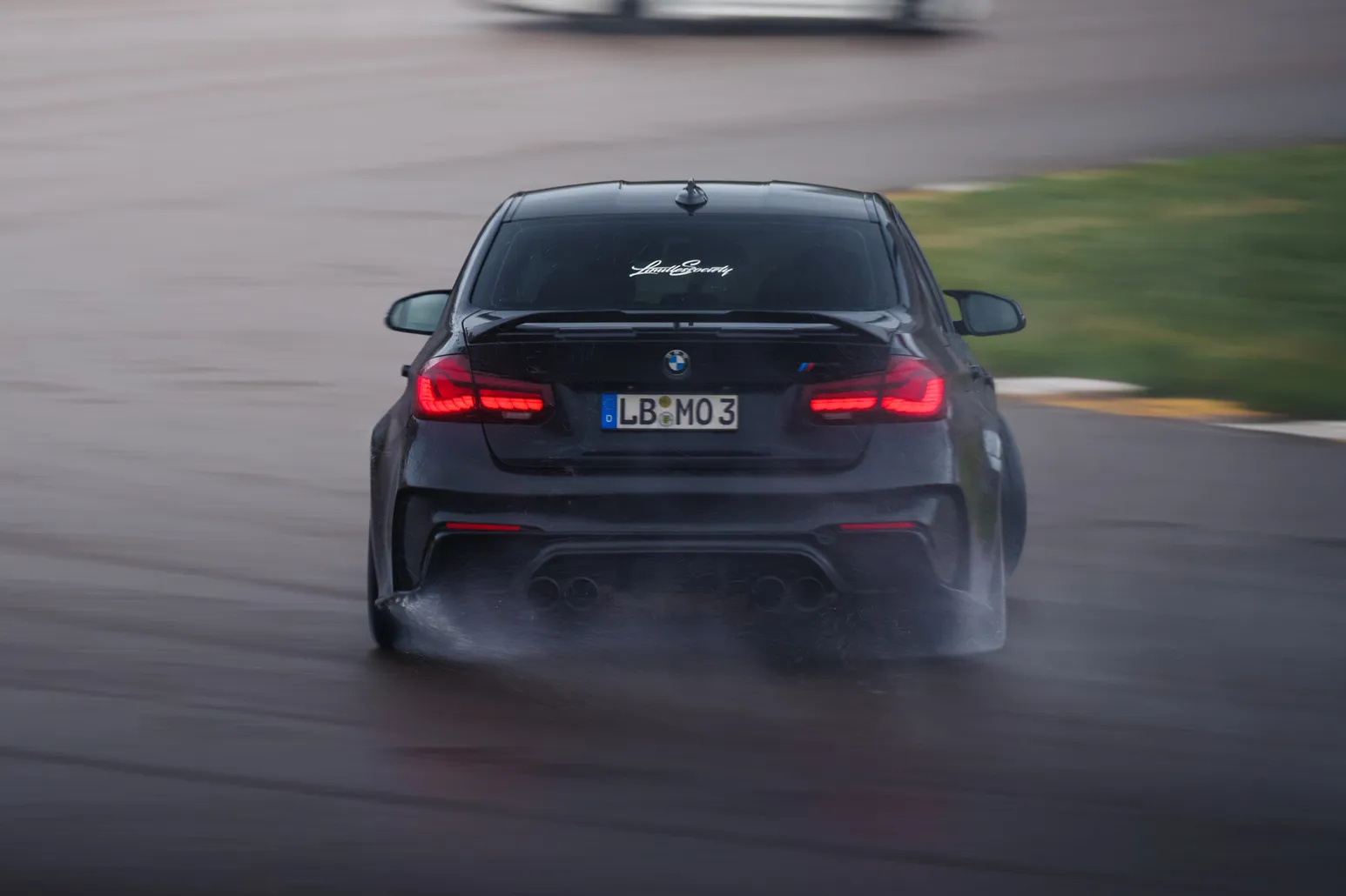 Black BMW M3 (F80) from behind with a plume of water