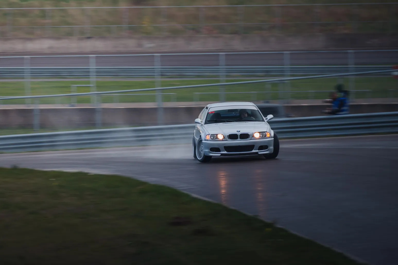 Silver BMW M3 (E46) drifting across the wet surface