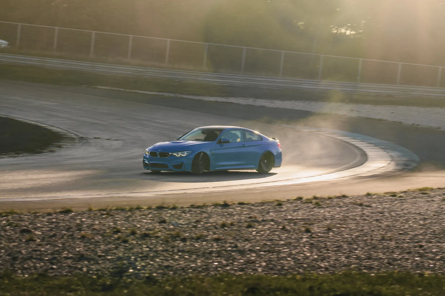 Blauer BMW M4 driftet im Gegenlicht durch Staub