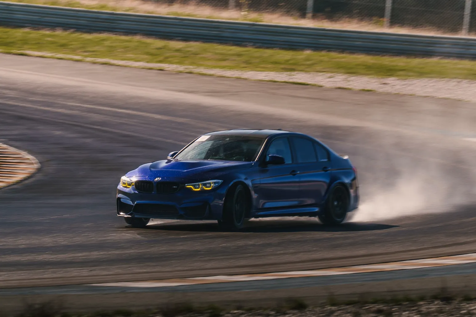 Blauer BMW M3 mit vollem Lenkeinschlag und dichtem Reifenqualm