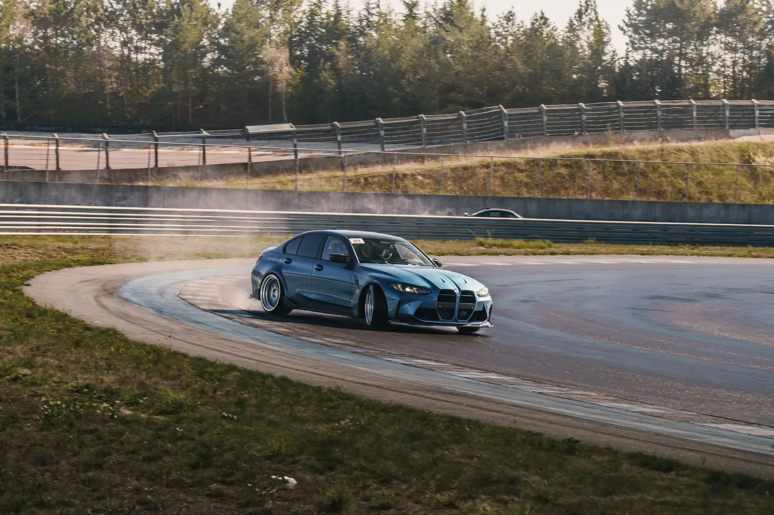 Blauer BMW M3 driftet mit Rauch im Infield