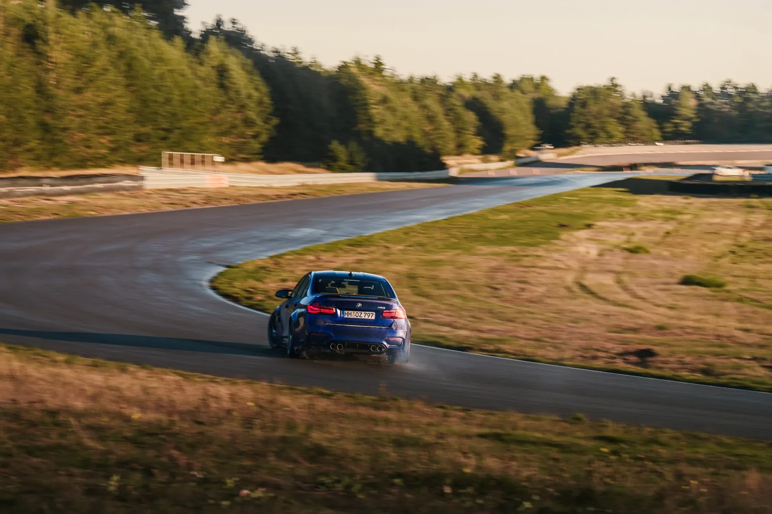 Blauer BMW driftet im Abendlicht durch die Kurve