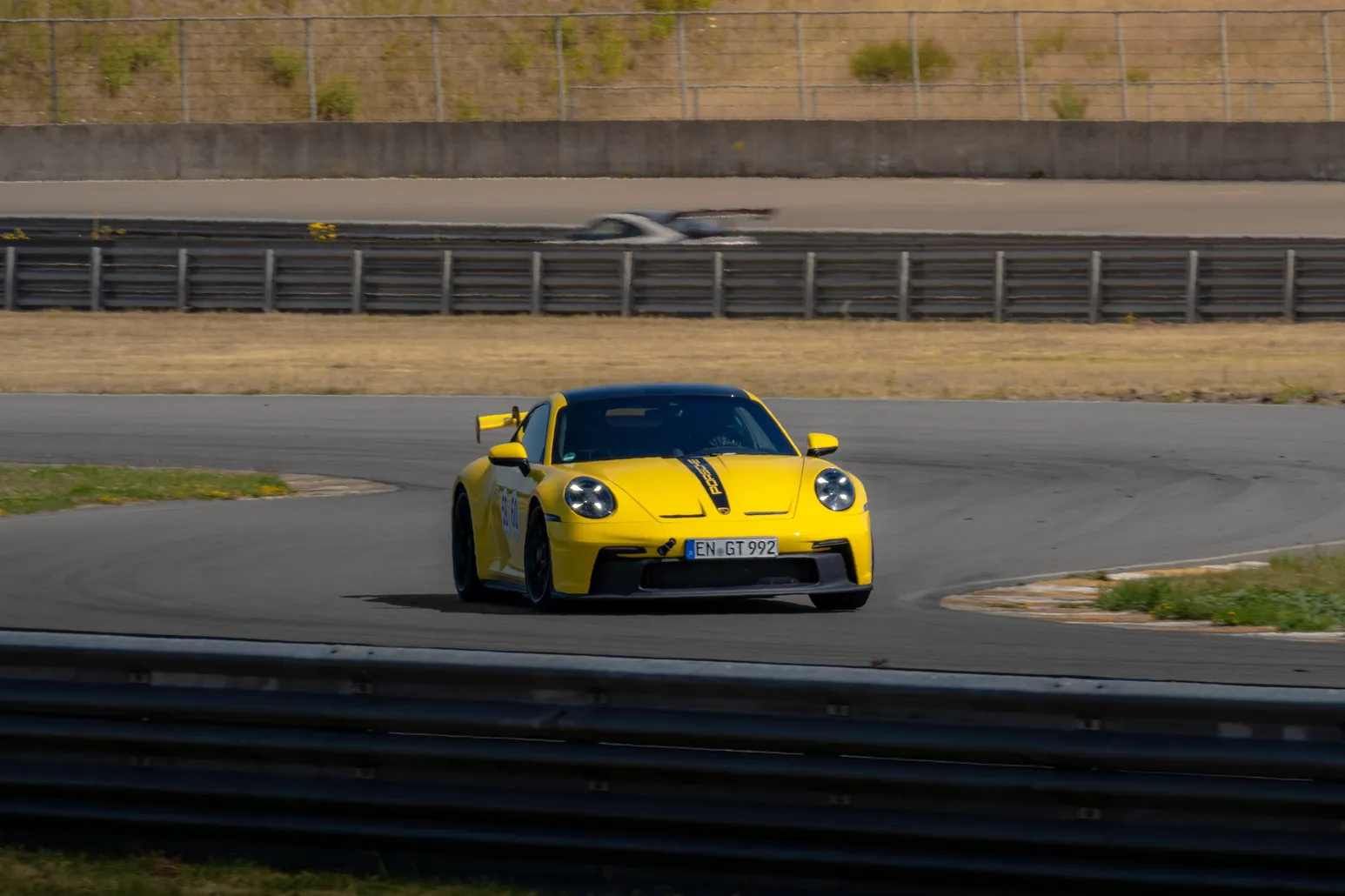 Gelber Porsche 911 GT3 beim Herausbeschleunigen aus einer Kurve, Frontansicht