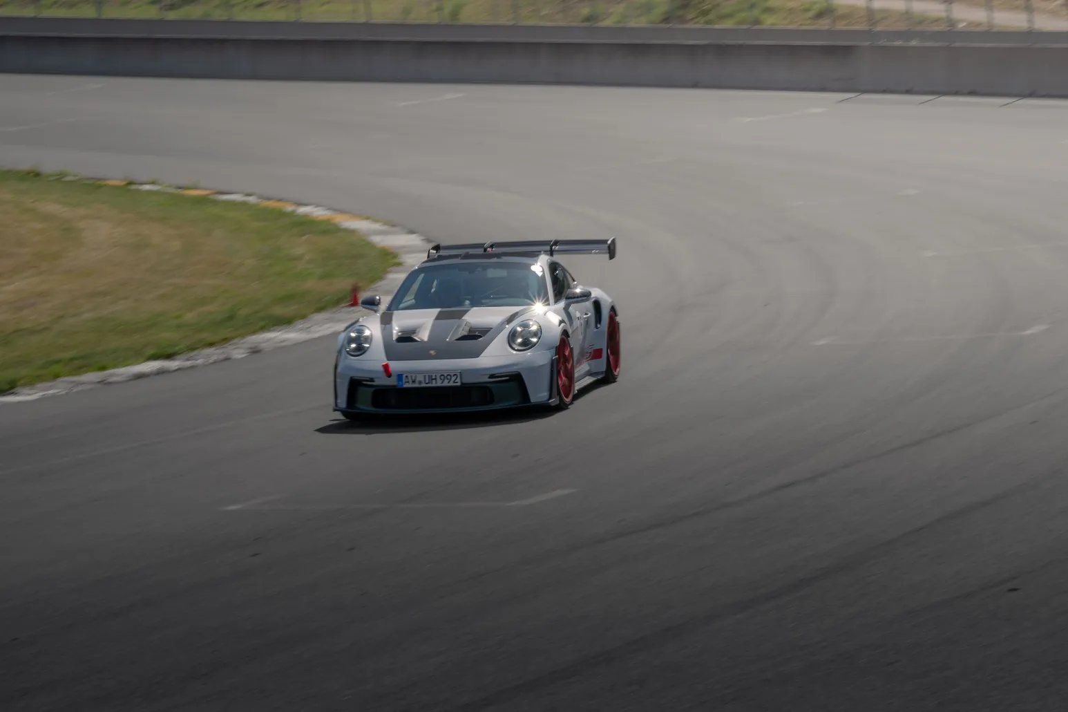 Silberner Porsche 911 GT3 RS mit Heckflügel in einer Kurve