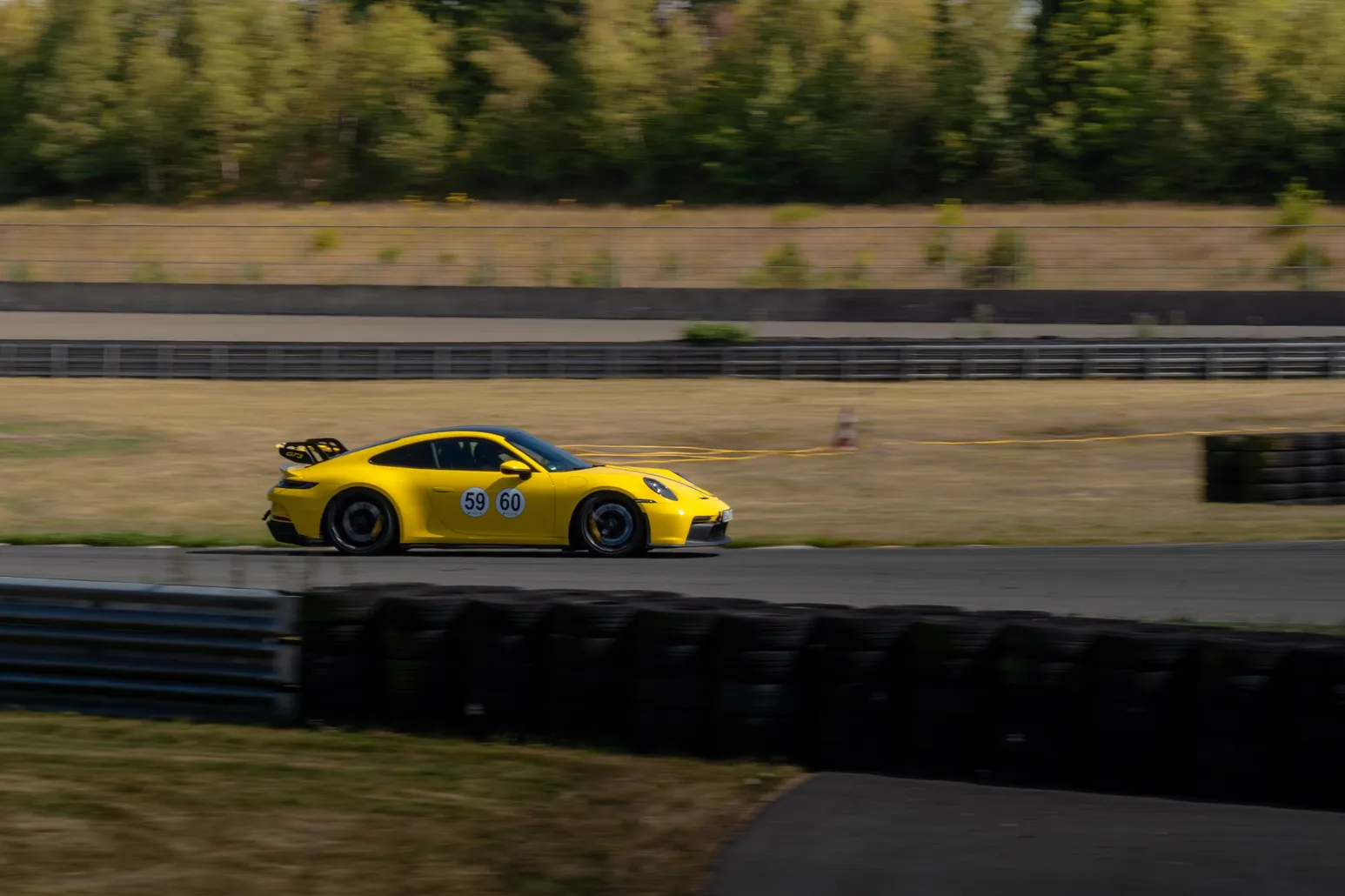 Gelber Porsche 911 GT3 als Mitzieher entlang der Reifenbarriere