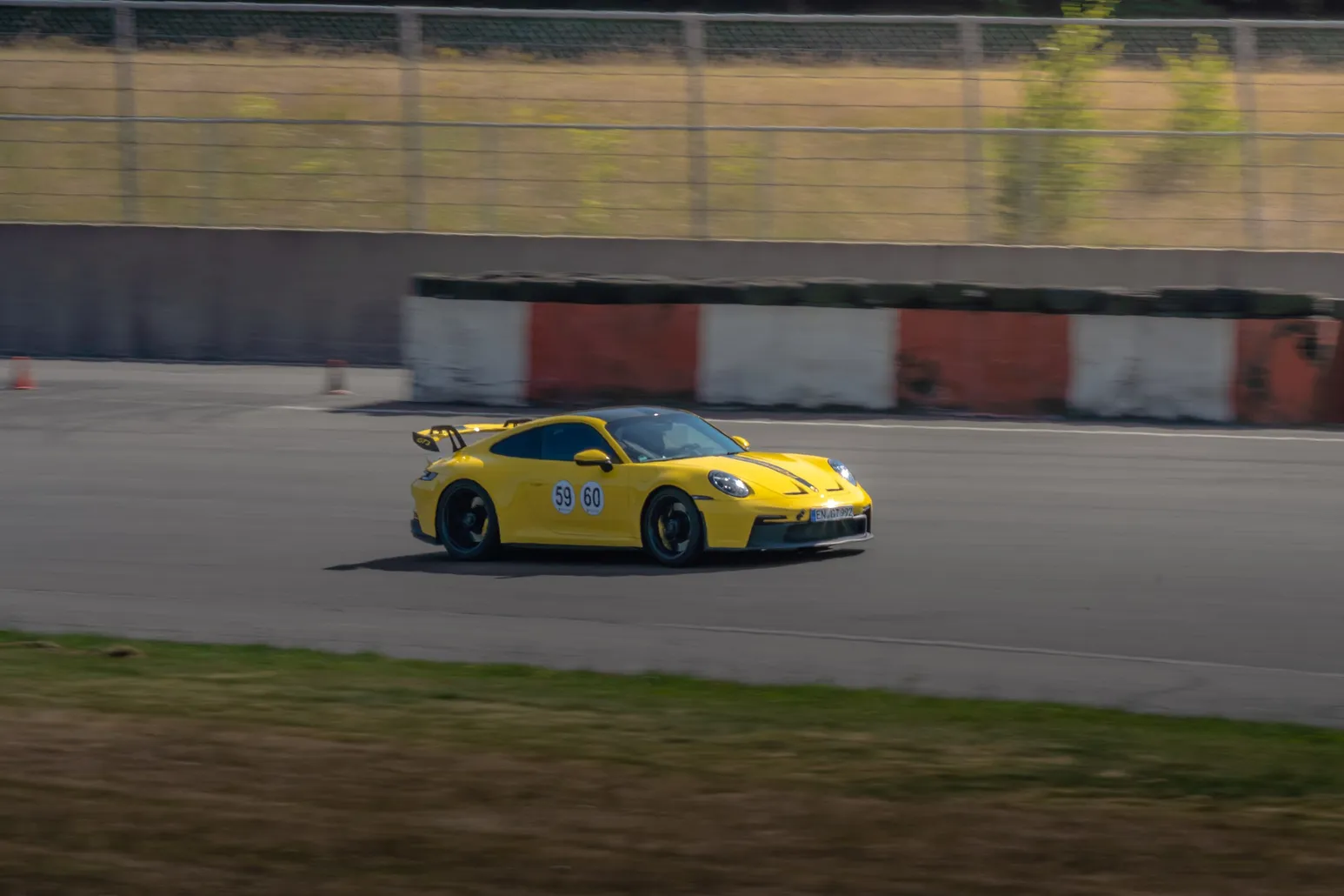 Gelber Porsche 911 GT3 an rot-weißen Curbs