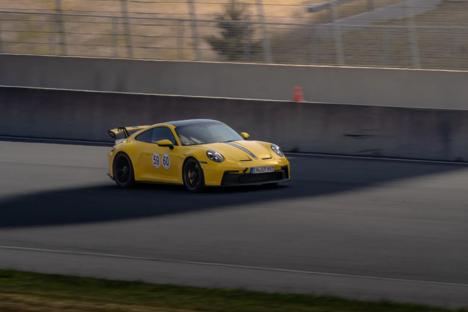 Gelber Porsche 911 GT3 auf der Strecke im tiefen Sonnenlicht