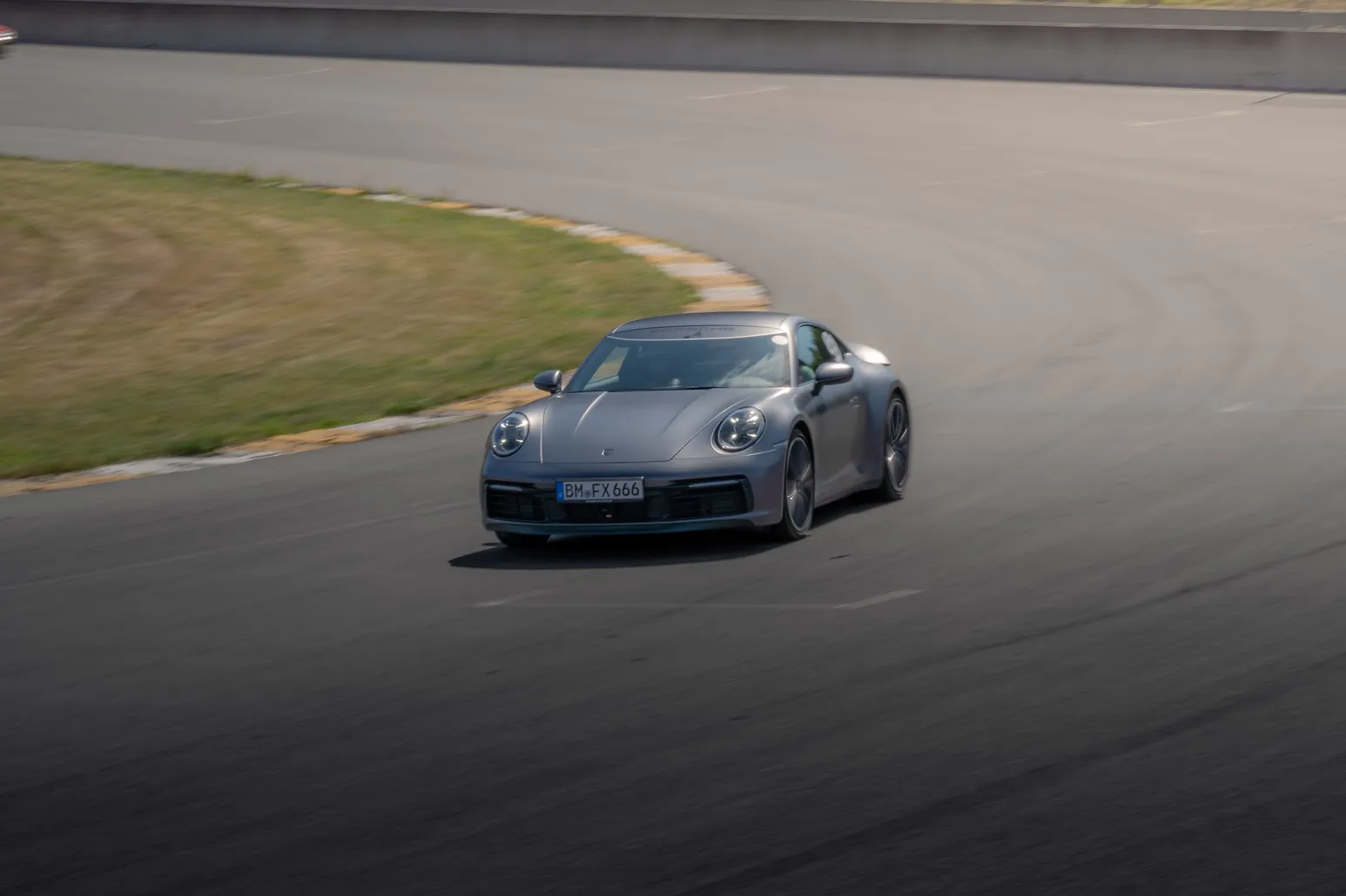 Grauer Porsche 911 beim Einlenken in eine Kurve