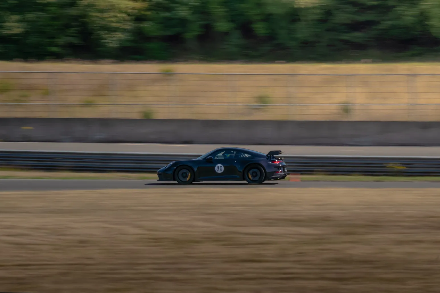 Schwarzer Porsche 911 GT3 RS tief auf der hinteren Geraden