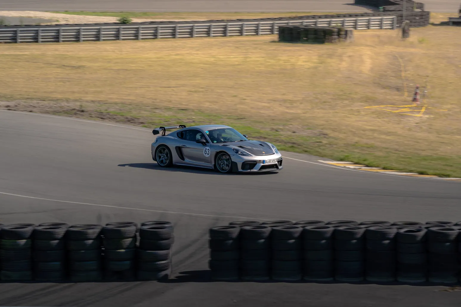 Grauer Porsche Cayman GT4 in einer Kurve über dem Reifenstapel