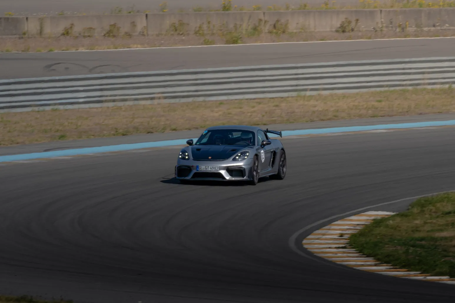Grauer Porsche Cayman GT4 frontal in einer Kurve