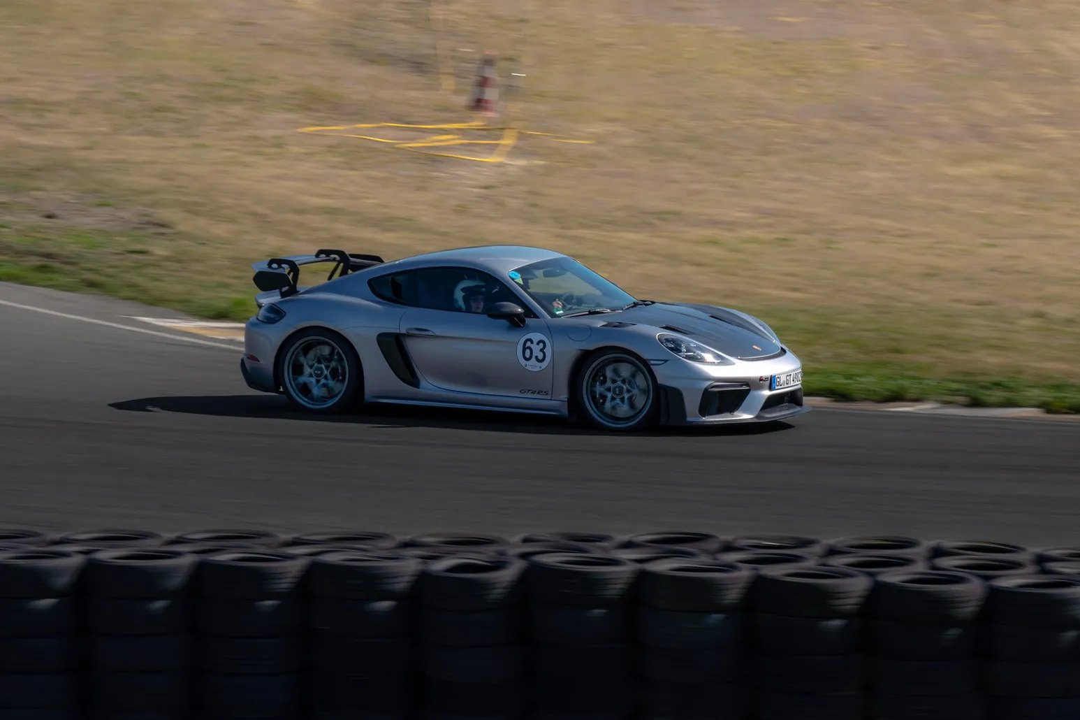 Silberner Porsche Cayman GT4 mit Startnummer 83 in einer Kurve