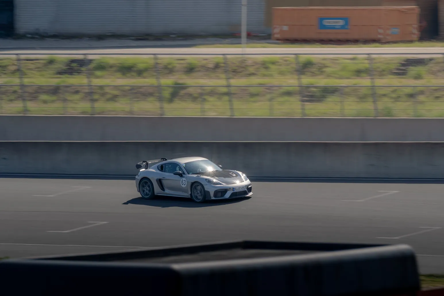 Silberner Porsche Cayman GT4 hinter der Boxenmauer