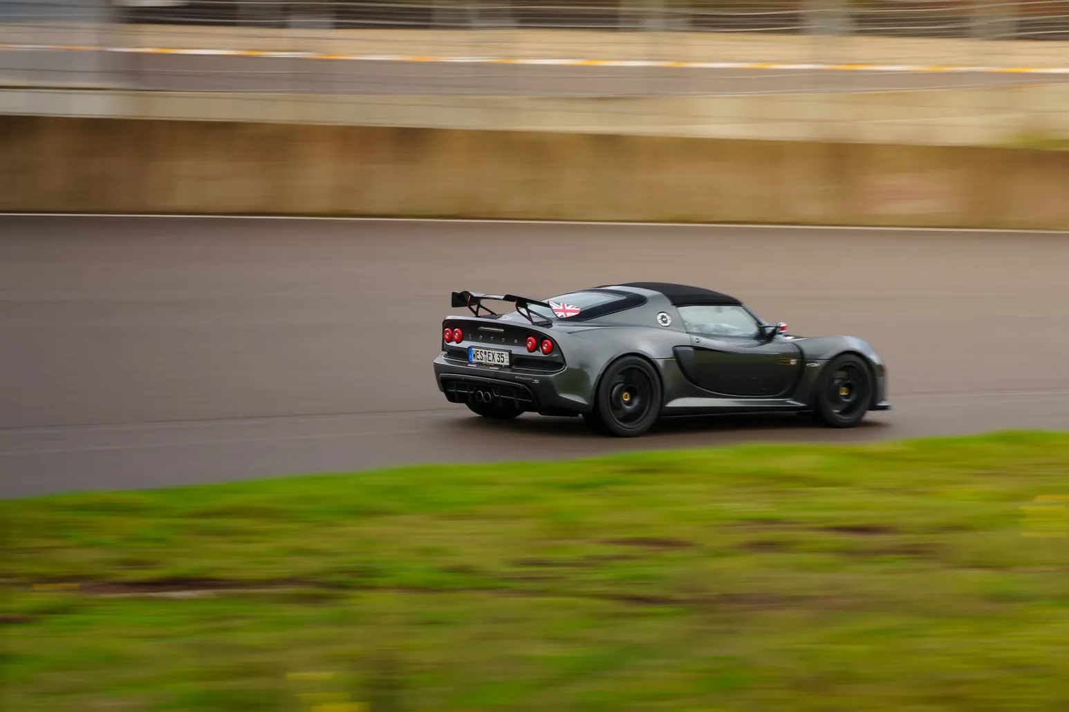 Lotus Exige panning shot against a concrete wall