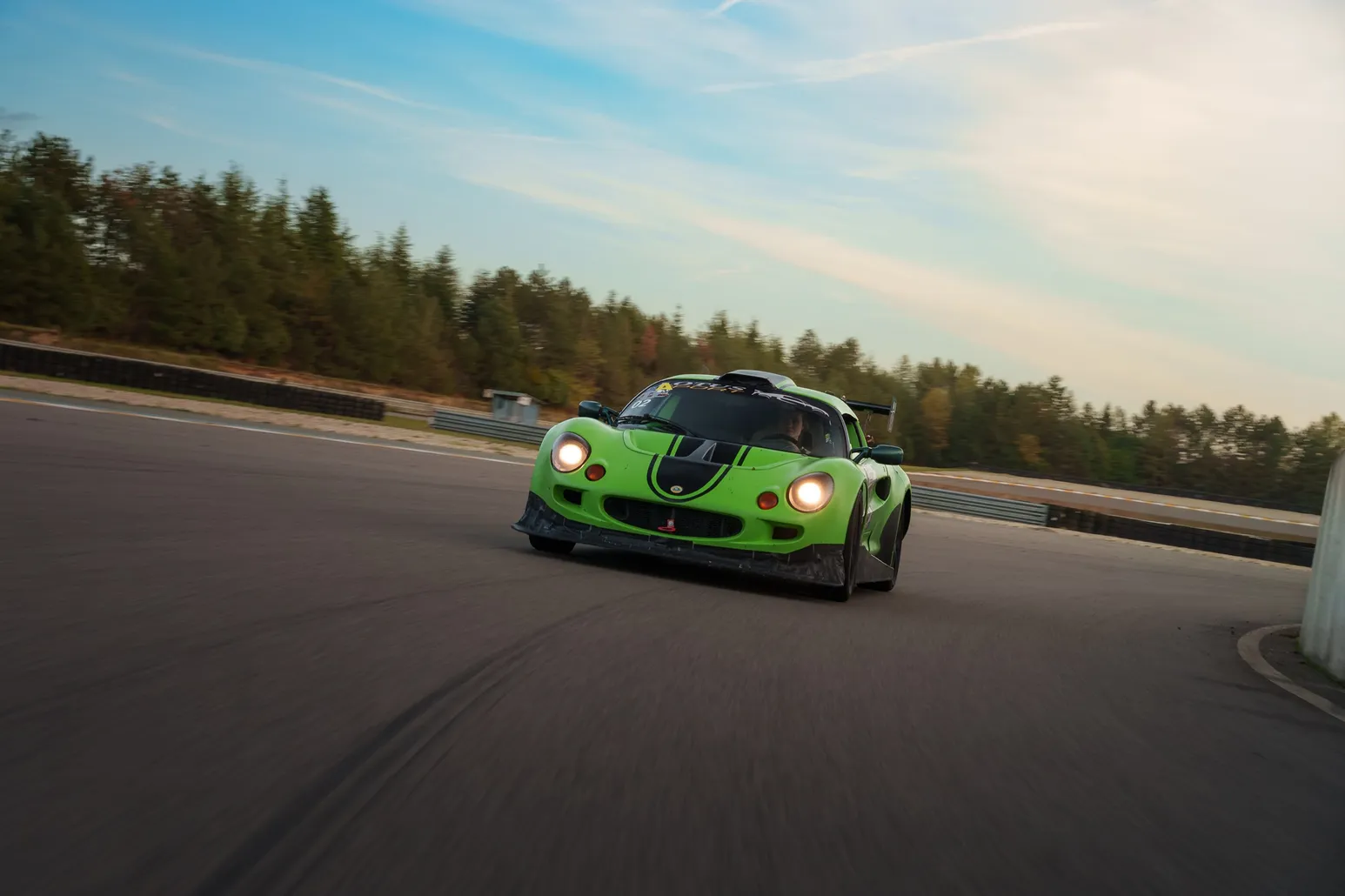Green Lotus Elise cornering under a blue sky