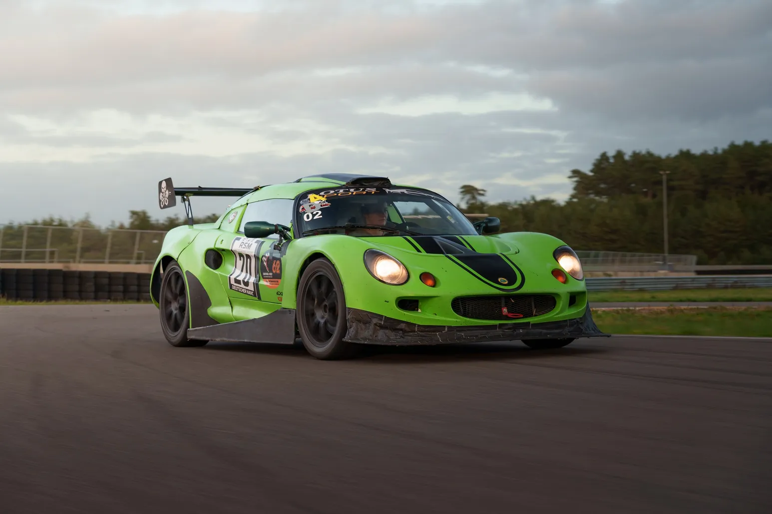 Green Lotus Elise with a large rear wing under a dramatic sky
